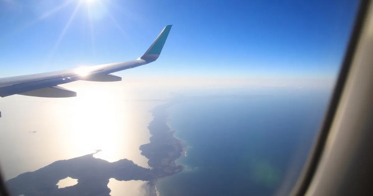 Aircraft wing above a coastline seen from a passenger window